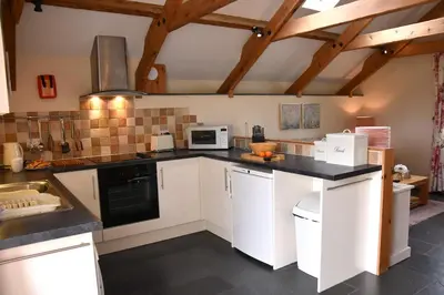 a kitchen with white cabinets and a black counter top at Oak Cottage in Tregoney