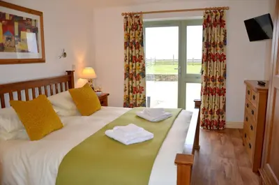 a bedroom with a bed with two towels on it at Willow Beautiful 3 bed accessible holiday cottages in Tregoney