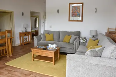a living room with a couch and a table at Willow Beautiful 3 bed accessible holiday cottages in Tregoney