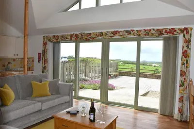 a living room with a couch and a large window at Willow Beautiful 3 bed accessible holiday cottages in Tregoney