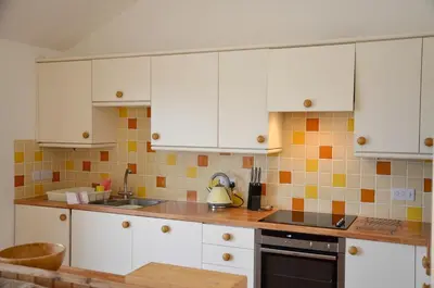 a kitchen with white cabinets and a sink at Willow Beautiful 3 bed accessible holiday cottages in Tregoney