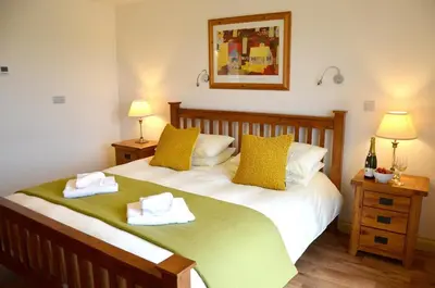 a bedroom with a bed with two towels on it at Willow Beautiful 3 bed accessible holiday cottages in Tregoney