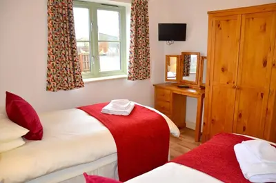 a bedroom with two beds and a window at Willow Beautiful 3 bed accessible holiday cottages in Tregoney