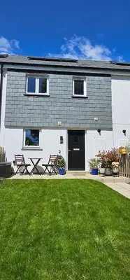 a house with chairs and a lawn in front of it at Meadowvine in Penryn