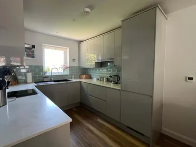 a large kitchen with white cabinets and a window at Meadowvine in Penryn