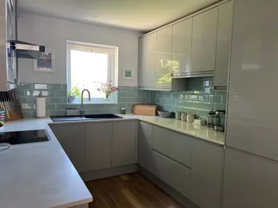 a kitchen with white cabinets and a sink and a window at Meadowvine in Penryn