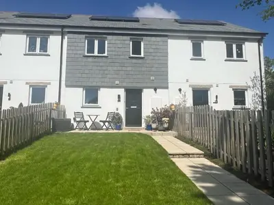 a white house with a fence and a yard at Meadowvine in Penryn