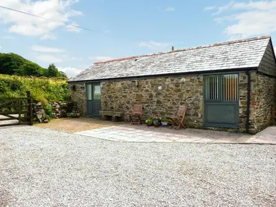 a stone cottage with blue doors and chairs at The Shippen - Uk49830 in Callington