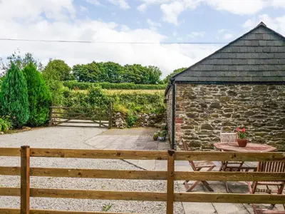 a garden with a wooden fence and a table at The Shippen - Uk49830 in Callington