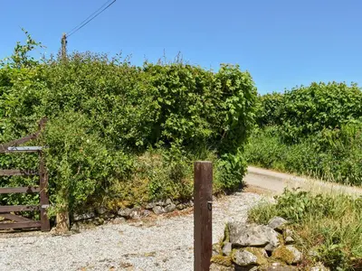 a wooden fence next to a dirt road at The Shippen - Uk49830 in Callington