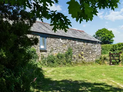 an old stone building with a window in a field at The Shippen - Uk49830 in Callington