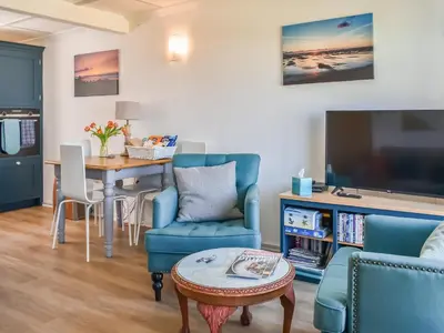 a living room with a table and chairs and a tv at Little Palms in Bude