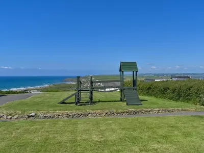 a park with a swing set on the side of a road at Little Palms in Bude