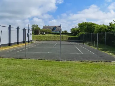 a tennis court in front of a fence at Little Palms in Bude