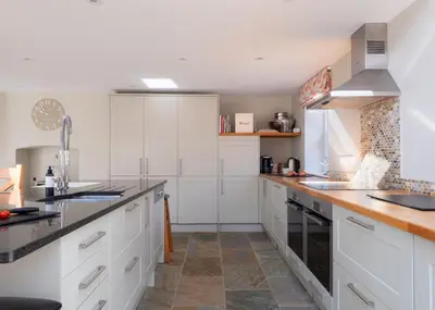 a kitchen with white cabinets and wooden counter tops at 1 The Terrace in Padstow