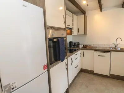 a kitchen with white cabinets and a refrigerator at Candle Croft in Redruth
