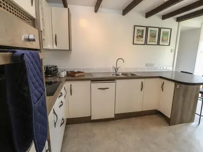 a kitchen with white cabinets and a sink at Candle Croft in Redruth