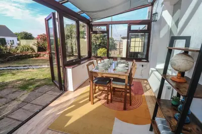 a dining room with windows and a table and chairs at Candle Croft in Redruth