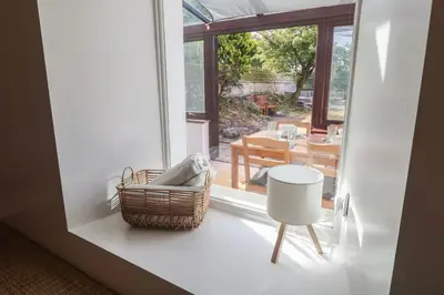 a room with a basket and a table and a window at Candle Croft in Redruth
