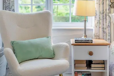 a chair with a green pillow on it next to a lamp at 2 Bed in Advent oc-o31790 in Lanteglos