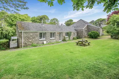 a stone cottage with a picnic table in a yard at 2 Bed in Advent oc-o31790 in Lanteglos