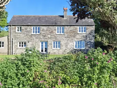 an old stone house with flowers in front of it at Tremorla in Boscastle