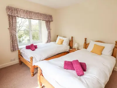 two twin beds in a room with a window at Tremorla in Boscastle