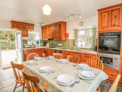 a kitchen with a table and chairs and a kitchen with at Tremorla in Boscastle