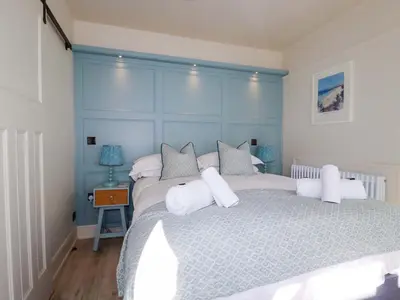 a bedroom with a large bed with a blue headboard at Beach View House in Newquay