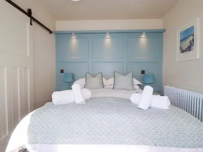 a bedroom with a large bed with a blue headboard at Beach View House in Newquay