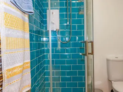 a blue tiled shower in a bathroom with a toilet at Foxglove in Bodmin