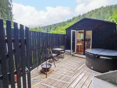 a black tiny house with a wooden deck at Foxglove in Bodmin