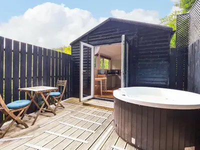 a black tiny house with a tub on a deck at Foxglove in Bodmin