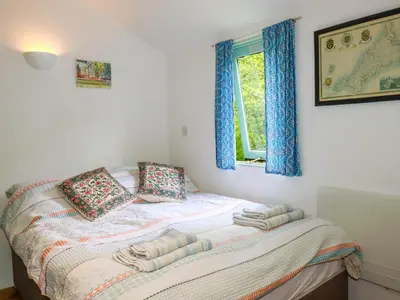 a bedroom with a bed with blue curtains and a window at Bluebell in Bodmin
