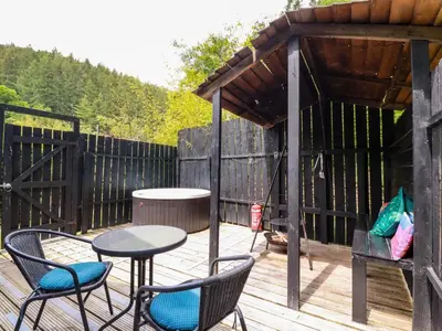 a patio with a table and chairs on a wooden deck at Bluebell in Bodmin