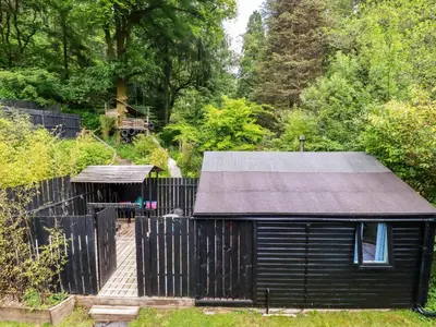 a black shed with a gate and a fence at Bluebell in Bodmin