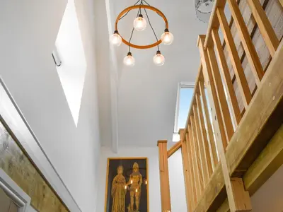 a stairway with a picture of two nuns and a chandelier at Roseland Retreat - Uk49838 in Truro