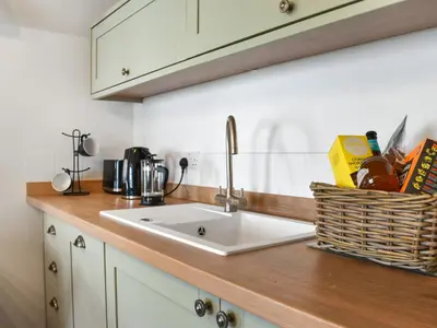 a kitchen counter with a sink and a basket of food at Roseland Retreat - Uk49838 in Truro