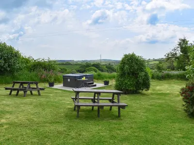 two picnic tables and a grill in the grass at Dairy Cottage - Uk49834 in Lanivet