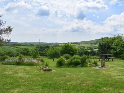 a picnic table in a garden with a view of the hills at Dairy Cottage - Uk49834 in Lanivet