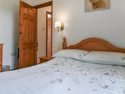 a bedroom with a large bed with a wooden headboard at Dairy Cottage - Uk49834 in Lanivet