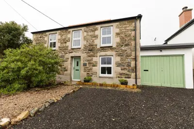 a stone house with a green garage at Parc Place in Gwithian