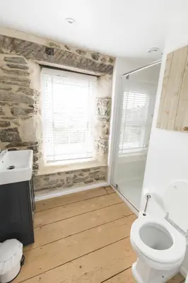 a bathroom with a toilet and a sink and a window at Parc Place in Gwithian