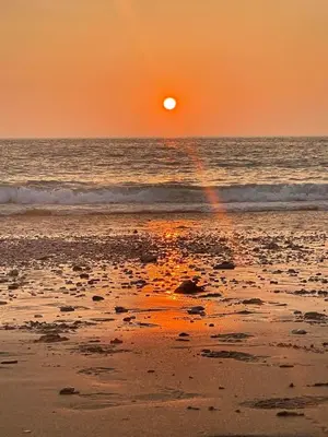 a sunset on the beach with a rainbow at Surf 'n' Sands in Porthtowan Beachfront Apartment in Porthtowan