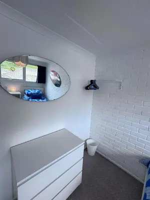 a white bathroom with a mirror and a toilet at Surf 'n' Sands in Porthtowan Beachfront Apartment in Porthtowan