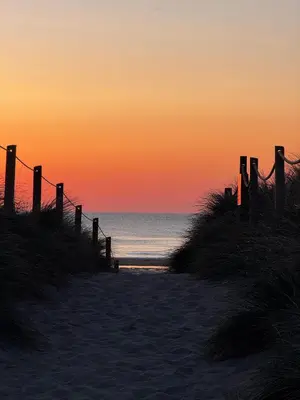 a sunset on a beach with the ocean at Surf 'n' Sands in Porthtowan Beachfront Apartment in Porthtowan