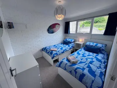 a small bedroom with two beds and a desk at Surf 'n' Sands in Porthtowan Beachfront Apartment in Porthtowan
