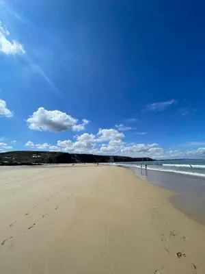 a beach with footprints in the sand and the ocean at Surf 'n' Sands in Porthtowan Beachfront Apartment in Porthtowan