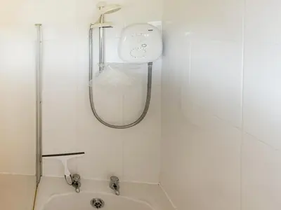 a white bathroom with a shower and a sink at Seven Bays Retreat in Padstow