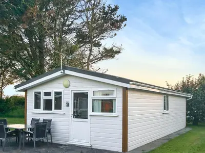 a small white shed with a table and chairs at Seven Bays Retreat in Padstow